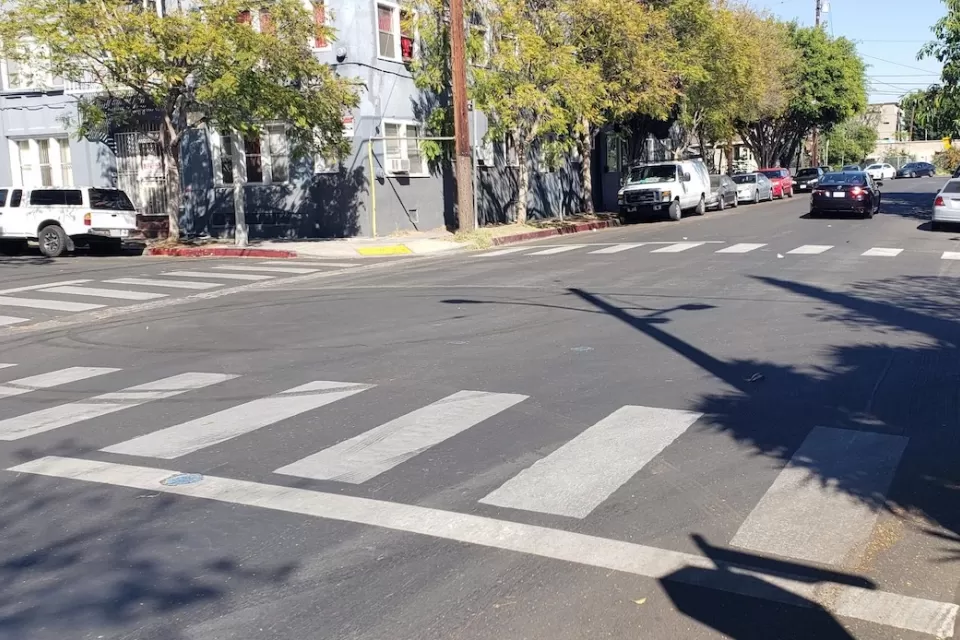 A white crosswalk painted by Crosswalk Collective LA in Los Angeles, California.
